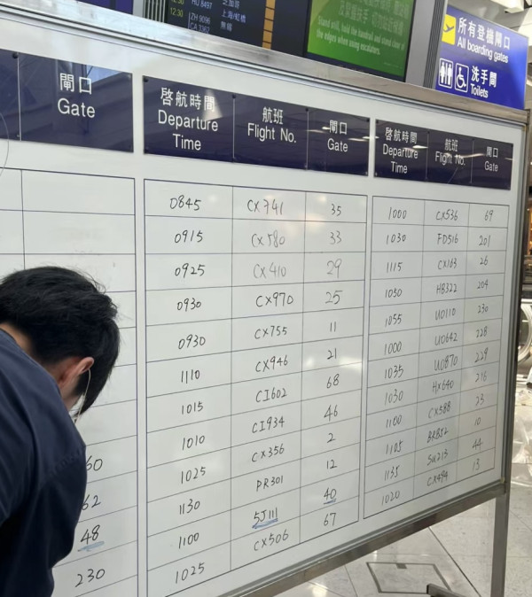 香港機場職員暫時用手寫資料代替電腦，顯示屏告知航班資料。（圖片來源：小紅書）