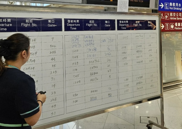 香港機場職員暫時用手寫資料代替電腦，顯示屏告知航班資料。（圖片來源：小紅書）