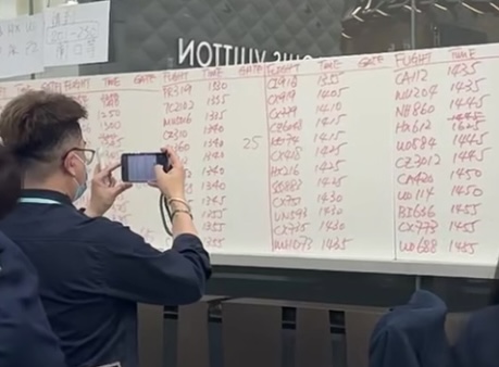 香港機場職員暫時用手寫資料代替電腦，顯示屏告知航班資料。（圖片來源：小紅書）