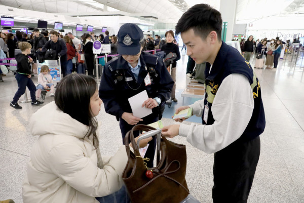 境處與警方於機場客運大樓內派發反詐騙宣傳單張。（圖片來源：HKET圖片庫）