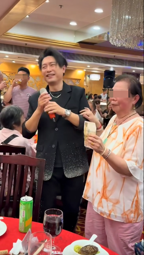 熱情阿婆從手袋中取出銀包並拿出一張$500紙幣，並把金錢塞到禢振華手上。