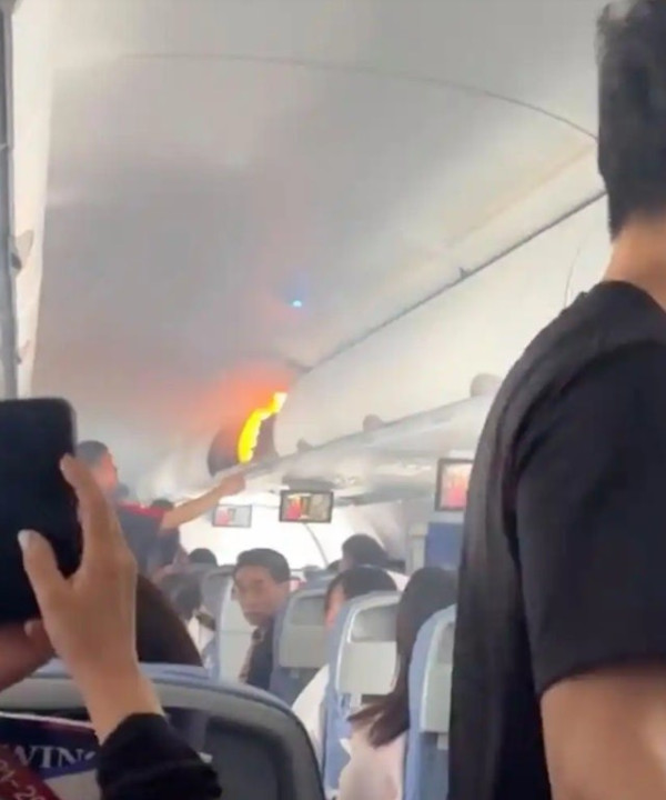 行李架上可見火光，火勢導致機艙內煙霧瀰漫。（影片截圖）