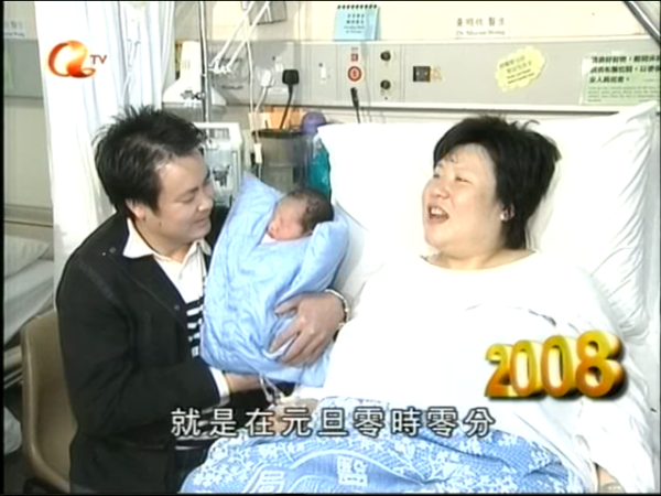 新聞主持形容BB「眼矇朦」，即使被大批傳媒包圍，仍在父母懷中睡得香甜。（網上截圖）