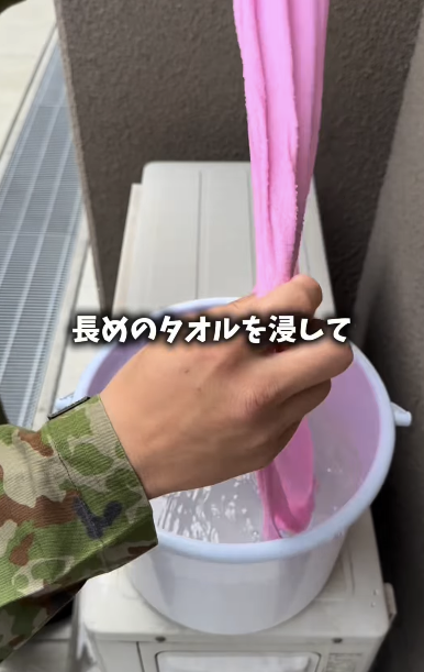 之後將毛巾另一端覆蓋於室外機頂部及背面位置垂掛至背面網狀位置，讓風吹動時持續保持濕潤效果。圖片來源：日本自衛隊