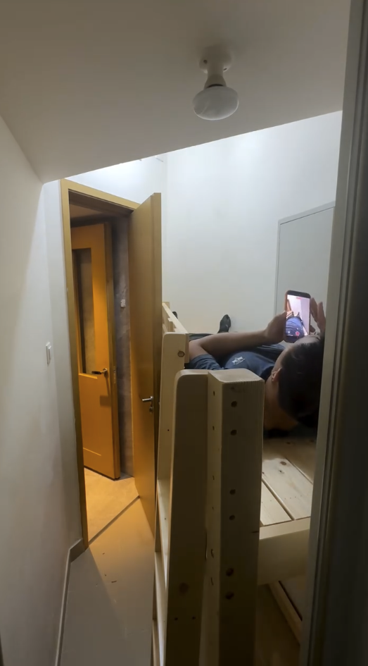 安裝員工示範躺上床，可見雙腳及身體幾乎頂住牆身，與電箱近距離相對。（截圖：Facebook）