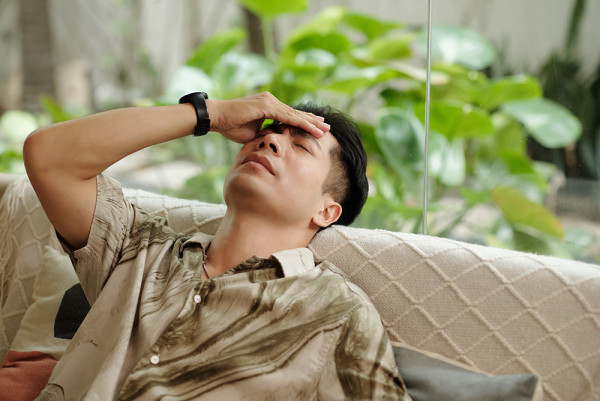 男士熬夜后扶额感到极度头痛与疲劳,反映肝功能下降及疲劳症状