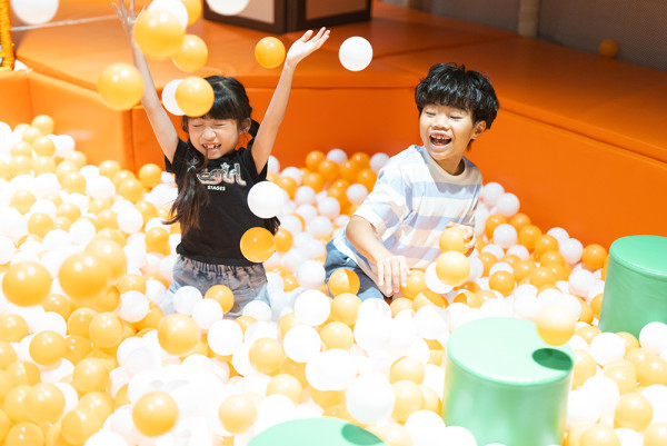 兩名小朋友在鋪滿黃白色波波池的KAKI LAND Play House內開心地玩耍潑球