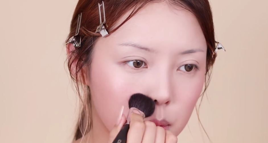 2 用散粉避開高光及胭脂部位，修飾臉部個別部位。