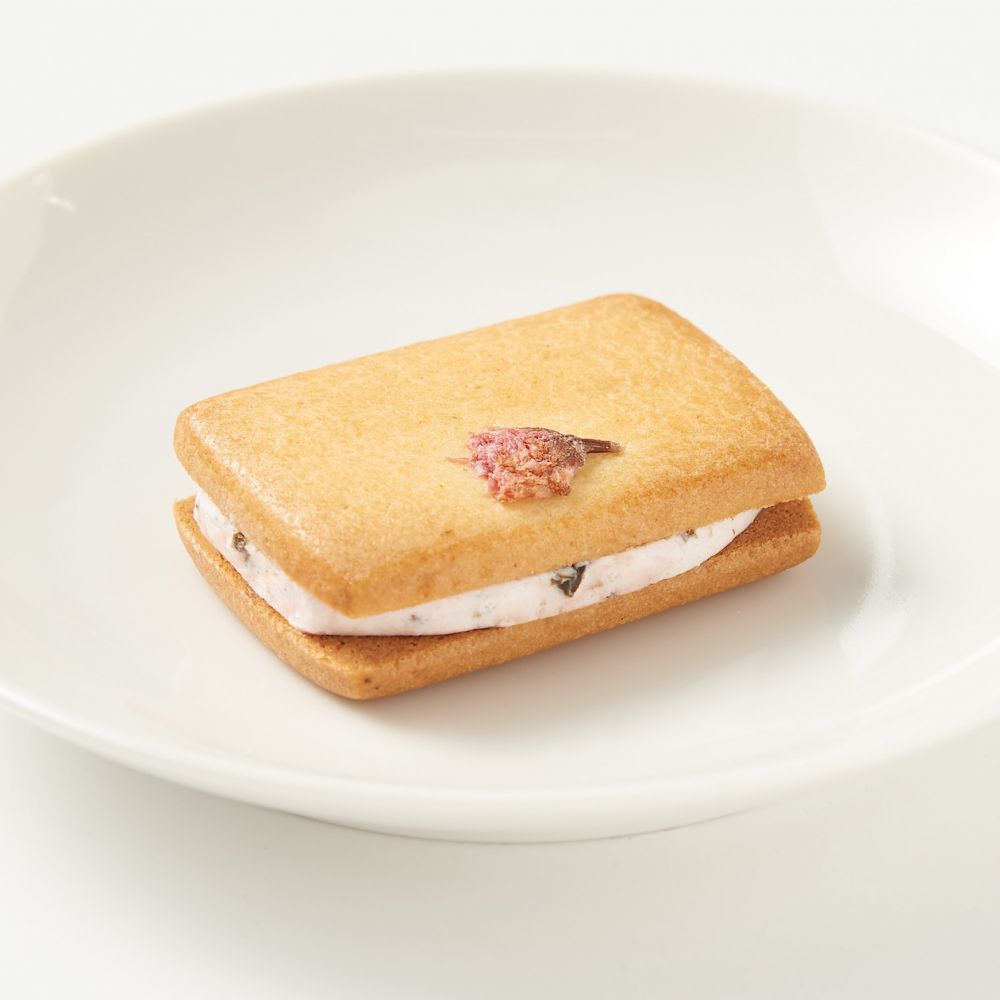 【櫻花奶油夾心餅乾  售價：120 日元（含稅） | 容量：1個 】 夾心奶油與櫻花葉揉在一起，上面放有櫻花花的餅乾。充滿櫻花香氣的奶油，搭配略帶鹹味鹽漬櫻花。