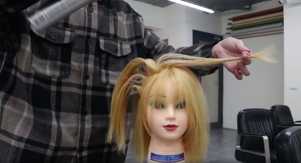 頭髮最頂的部分要拉向對角的位置，然後往髮根部分噴上定型噴霧