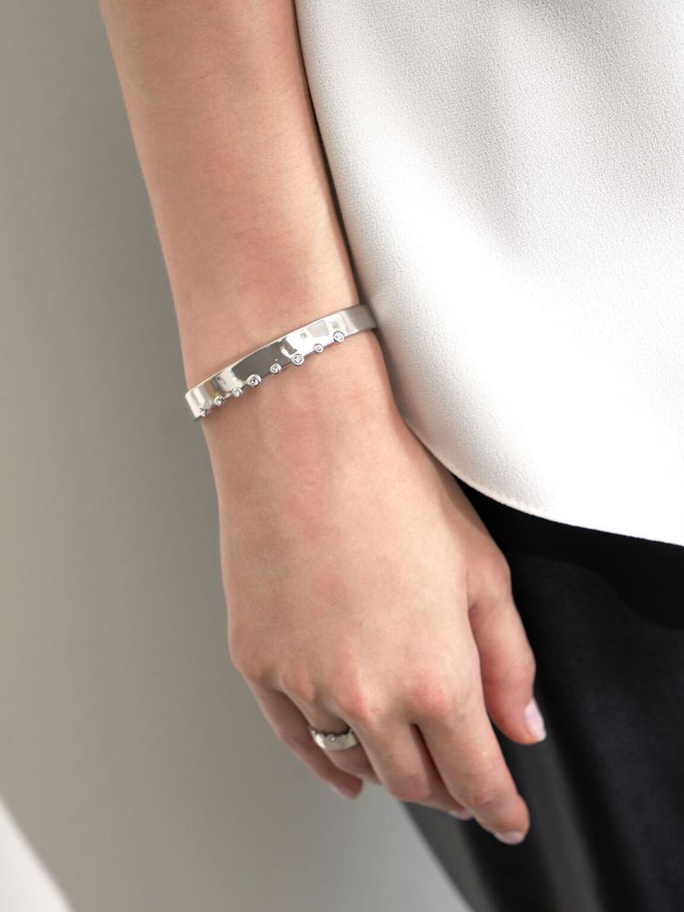 比細緻鍊條更具個性的金屬手環，賦予穿搭強烈的魅力，搭配小巧水晶點綴出微奢華的女人味。