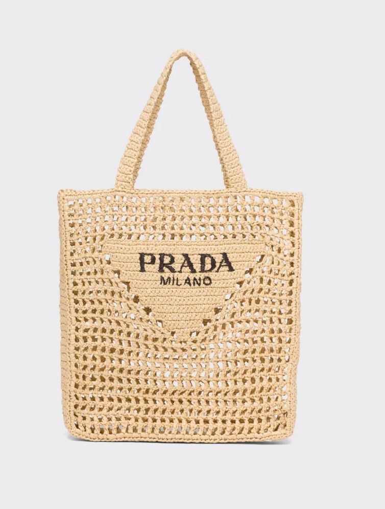 以酒椰葉（Raffia）編織而成的設計亦充滿夏日風情。手袋正中是Prada的倒三角 Logo以及刺繡字樣，設計簡潔清新，任何年齡也能輕鬆駕馭。