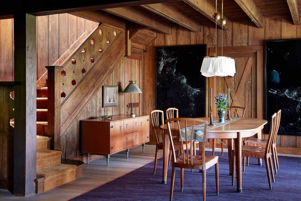 飯廳以老式純木餐桌和椅子佈置，旁邊是餐具櫃，地面鋪上紫色地毯。（圖片來源：architecturaldigest）