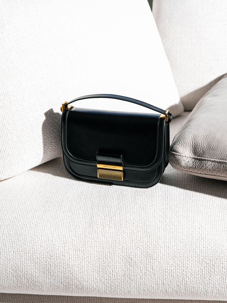 Charlot 金釦包是品牌的熱賣袋款之一！寬縫線設計與皮革的光澤感讓包款更具懷舊氛圍，黑金配色低調卻帶有知性氣質，使穿搭造型提升高級感的完美點綴。