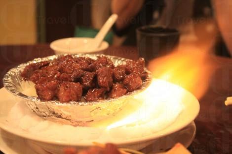 黑椒牛柳粒置於滲了火酒的鹽上，上桌時一點火，極盡娛樂性。（關璇攝）