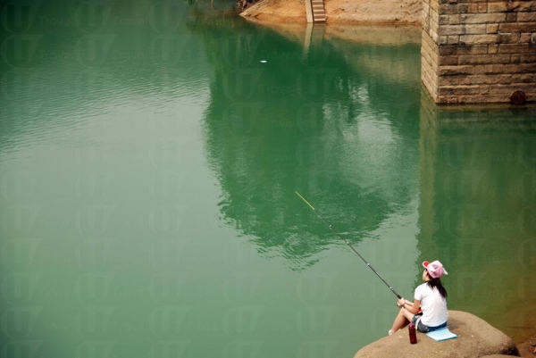 湖邊遊人在旁悠然自得釣魚。