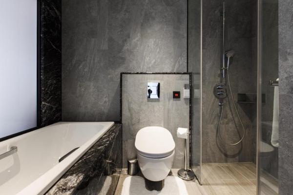 浴室以灰色為主，透明玻璃分隔加強整體空間感，不會有狹窄感。