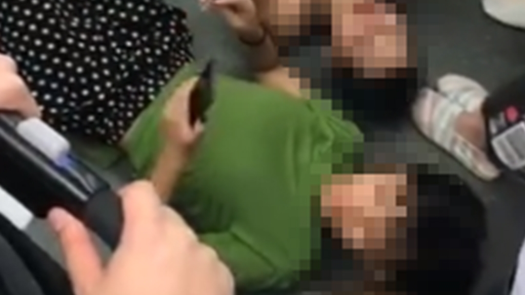 中國女子橫躺地鐵車廂地板玩電話